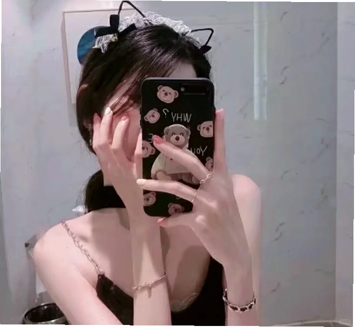 Cô gái che mặt bằng điện thoại khi đứng trước gương